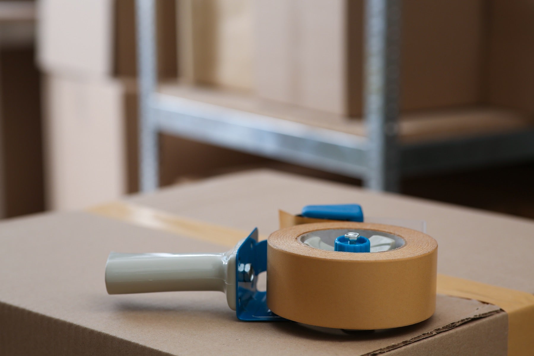 Handabroller mit Paketband auf einem Versandkarton im Lager